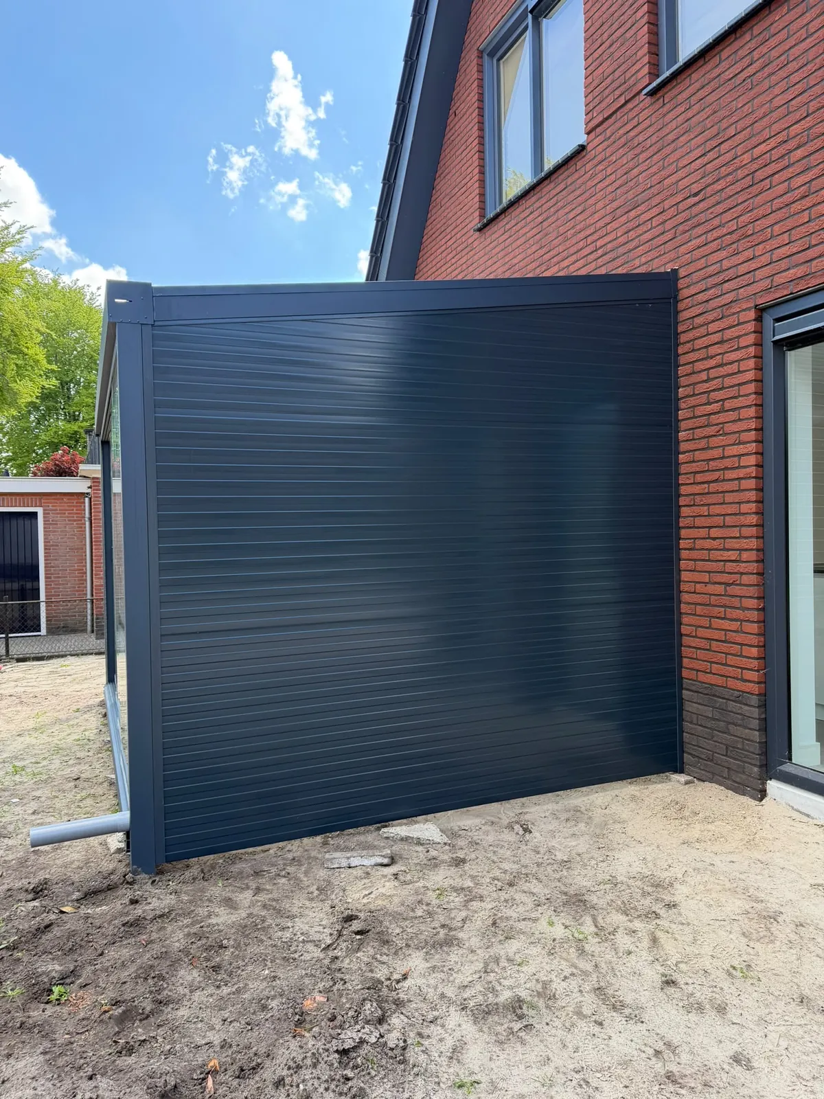 Detail van een antraciet zijwand tegen de gevel