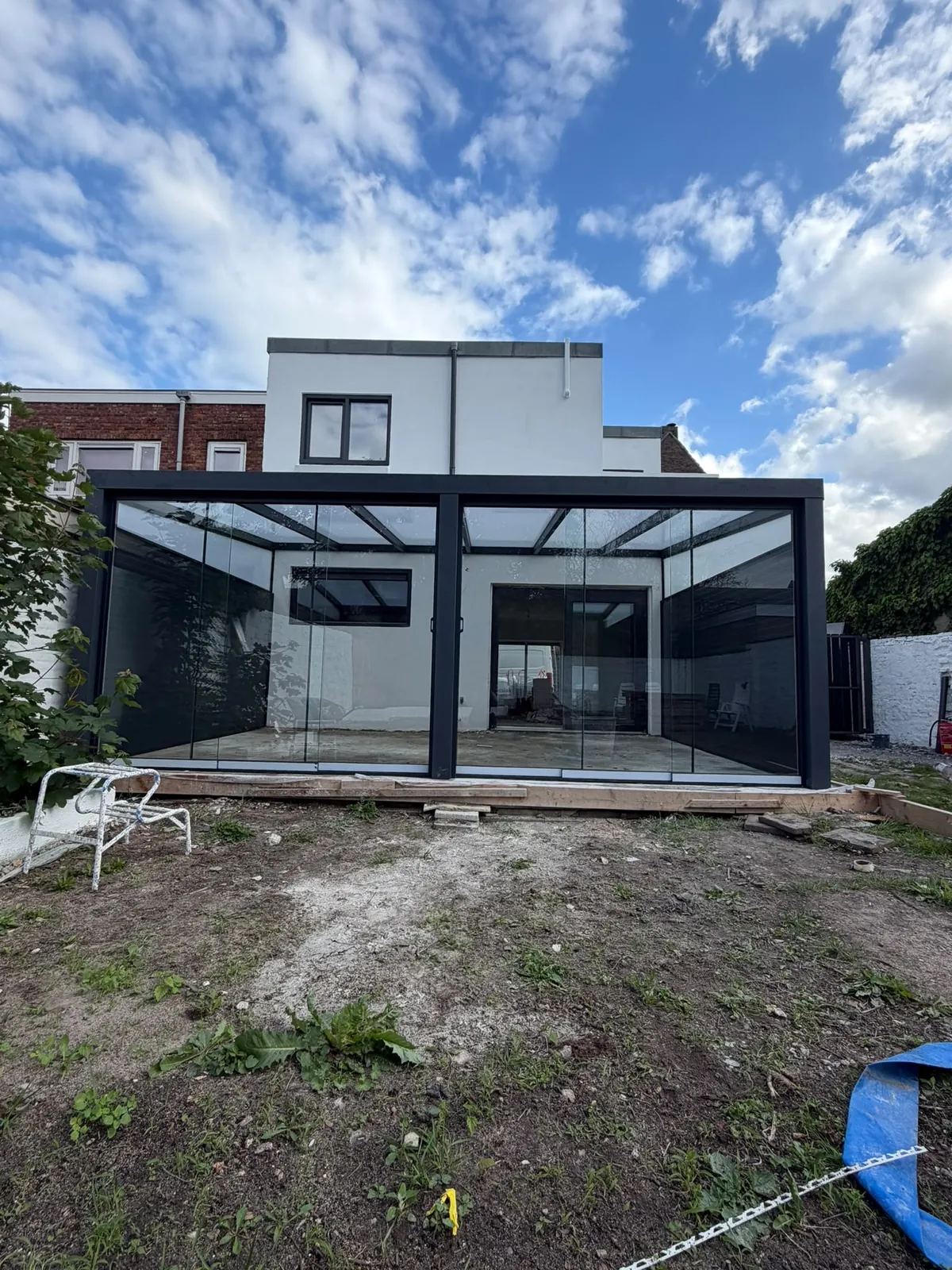 Glazen veranda aan een witte woning tijdens de werkzaamheden